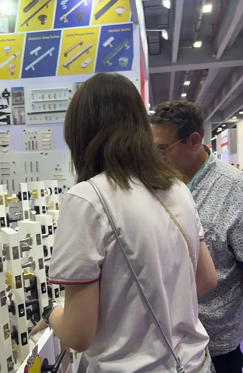 Un groupe d'acheteurs compare l'ensemble du mur de quincaillerie sur le stand Wekis le deuxième jour