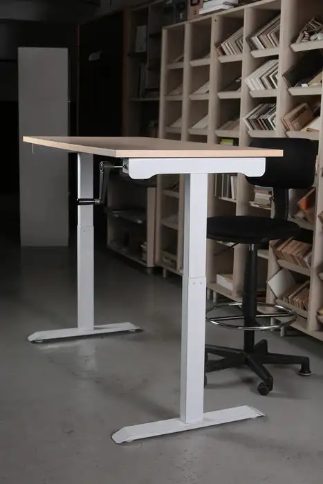 A manual crank table base showing the mechanical lifting mechanism — the repetitive physical strain of cranking is a hidden cost that contributes to staff turnover.