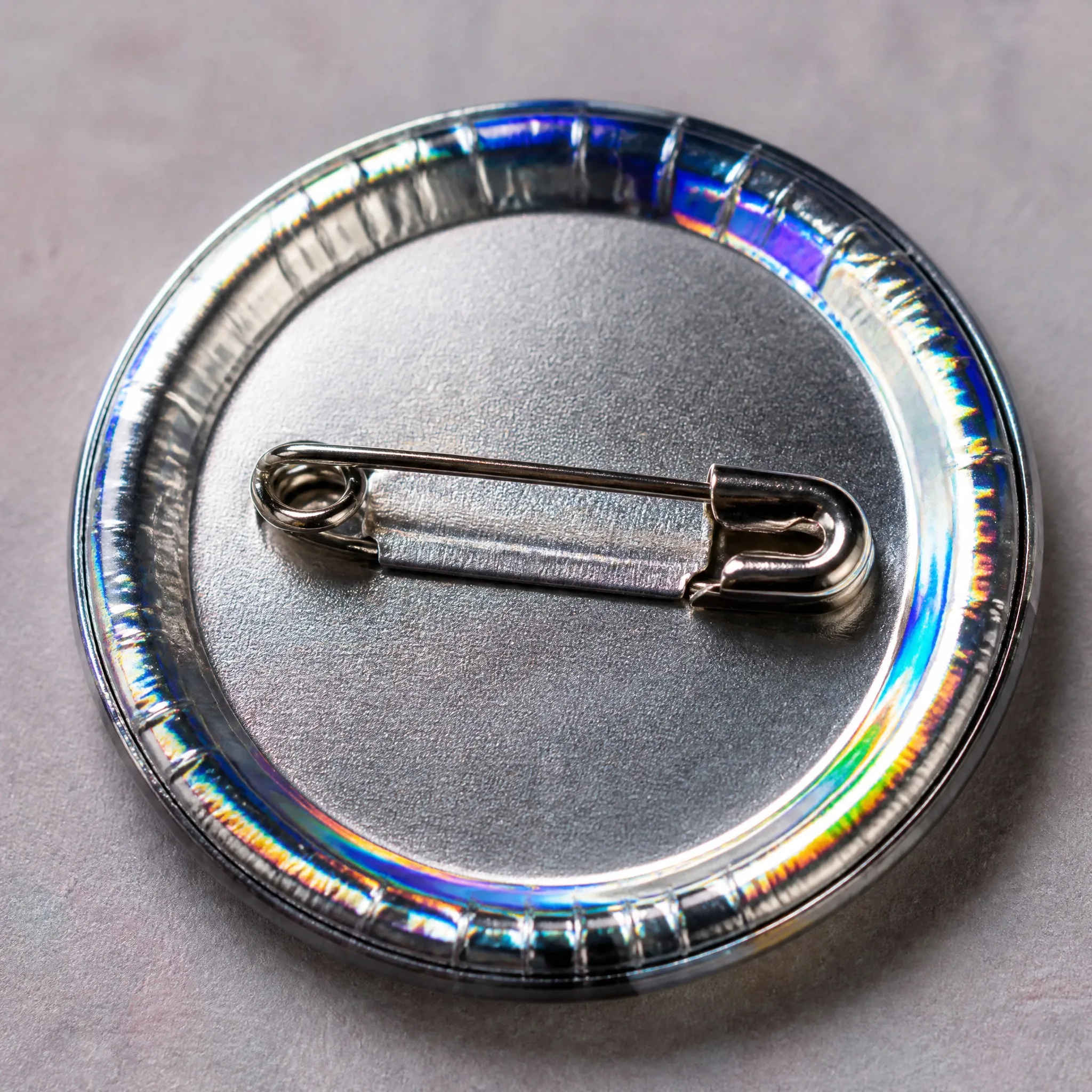 Holographic film and safety pin back detail of button badge