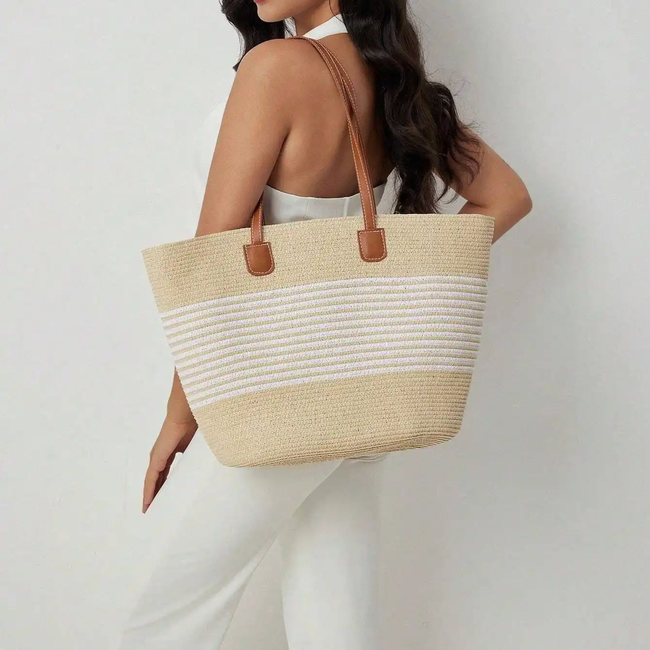 Straw woven beach tote with leather handles worn on shoulder