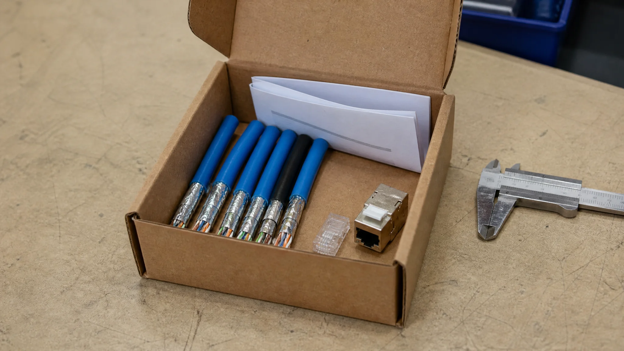 Open sample box with cut lengths of Cat6A cable, a plug, a jack and a test report