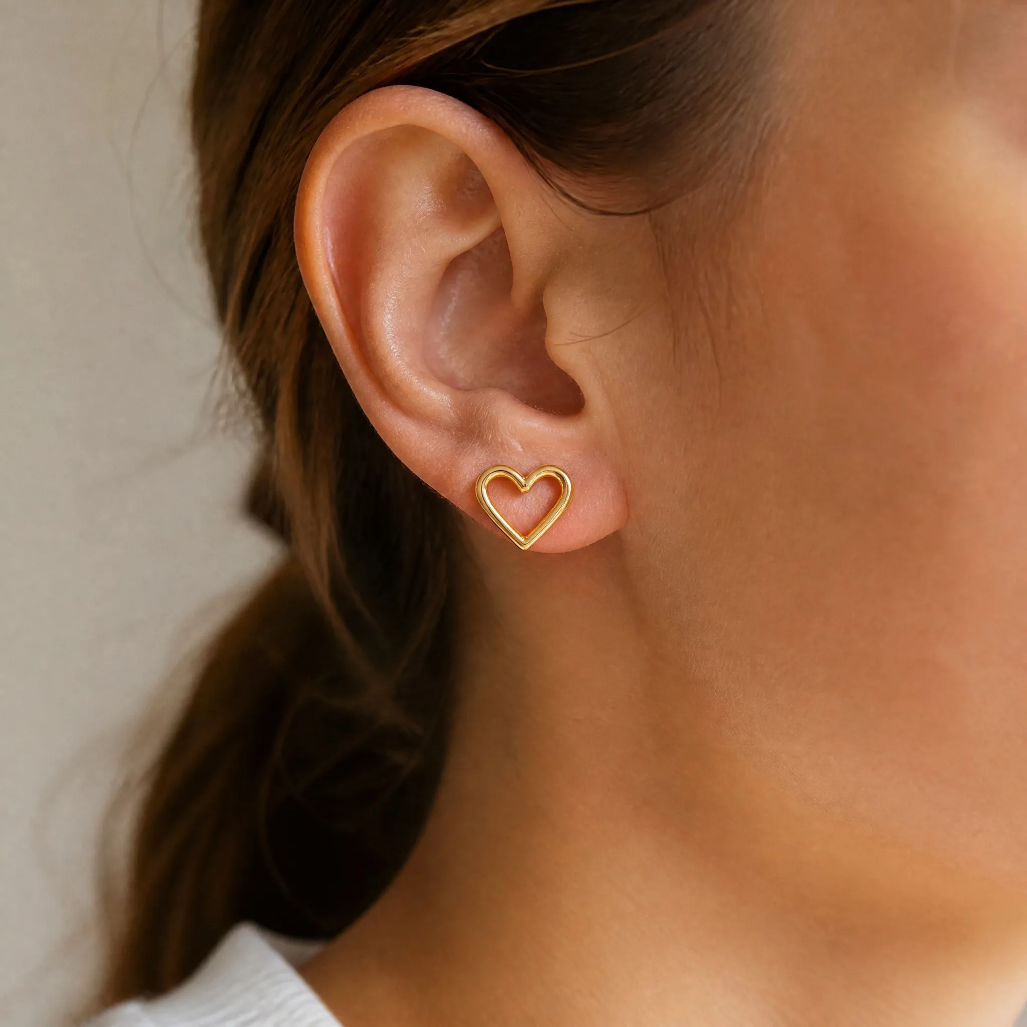 Wearing gold heart stud earrings
