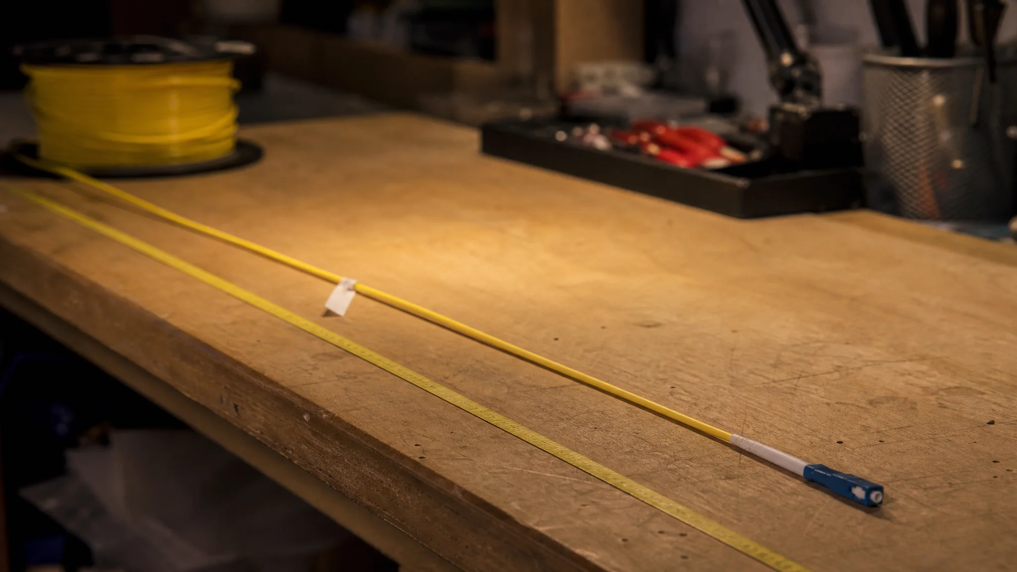 Fiber cable being measured along a bench with a tape and a tag