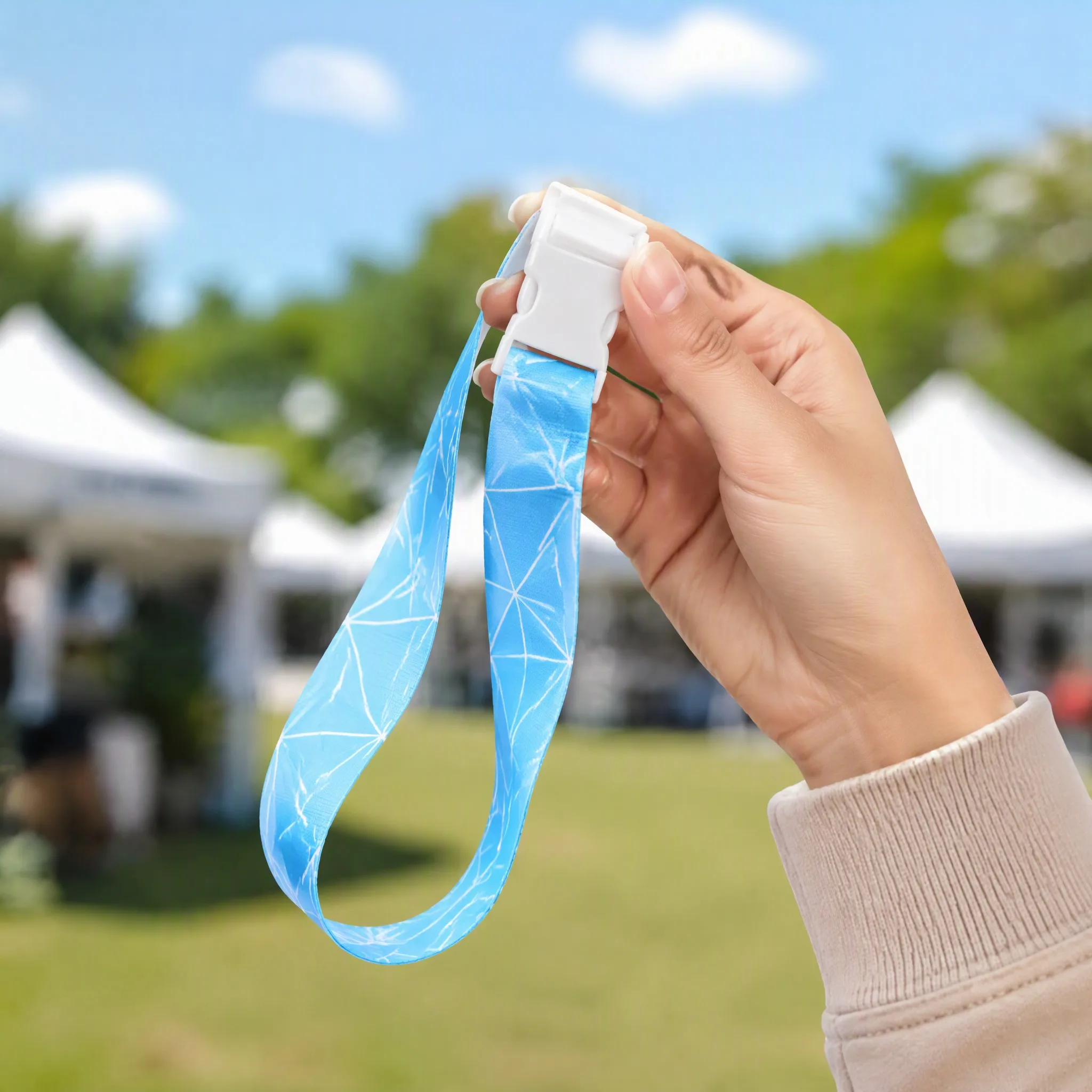 Hand holding silicone lanyard at an outdoor tented event