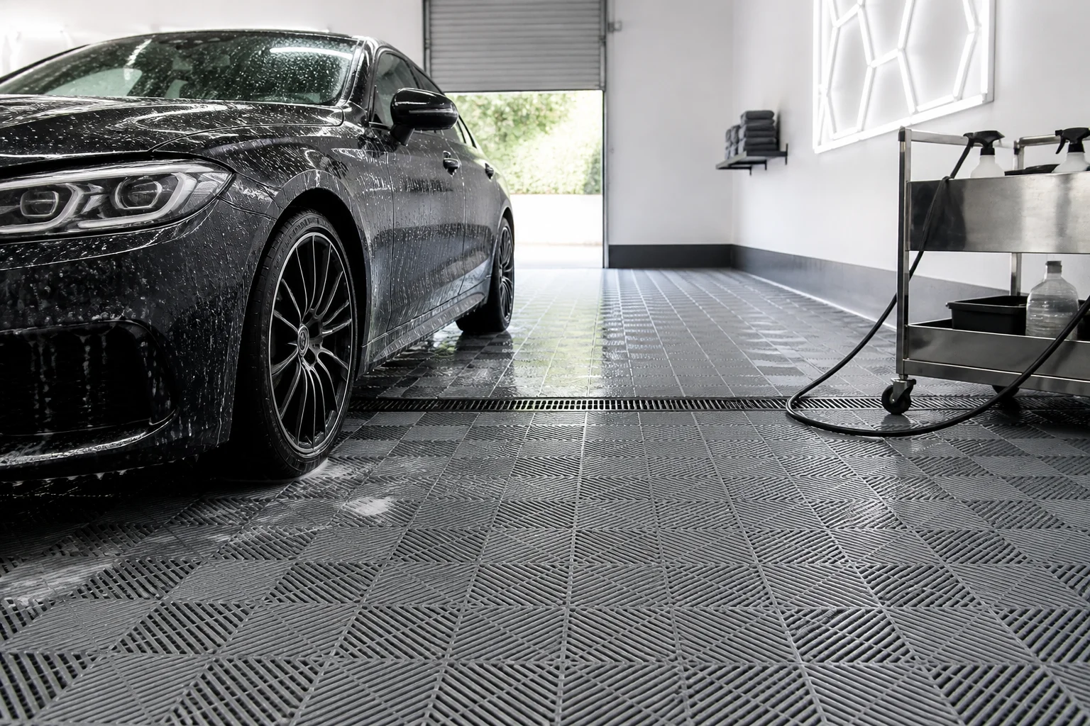 Car being washed in a professional detailing bay floored with interlocking garage floor tiles and a floor drain channel