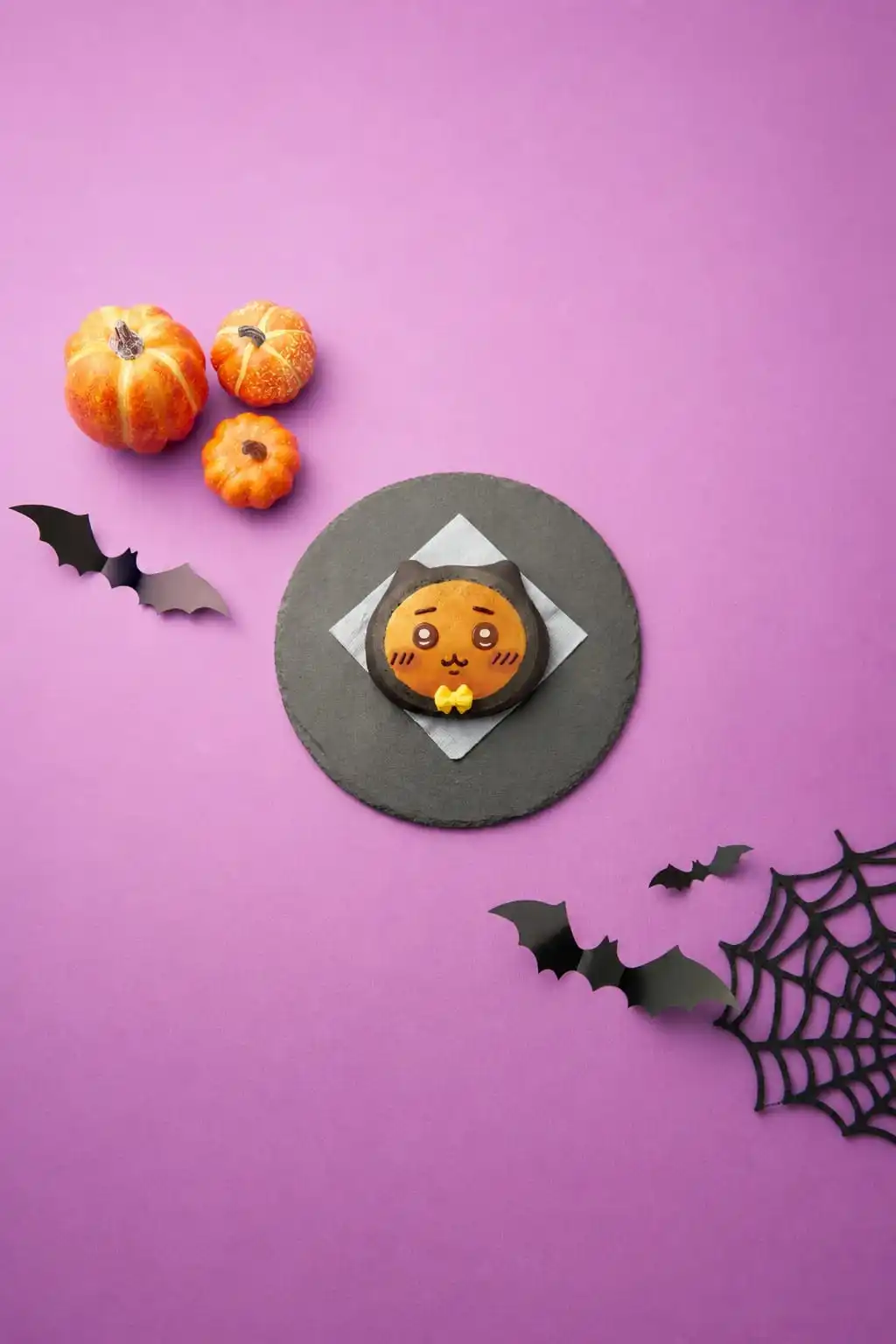 A black-cat Halloween bread with a Usagi-style face on a slate plate with pumpkins and bat decorations