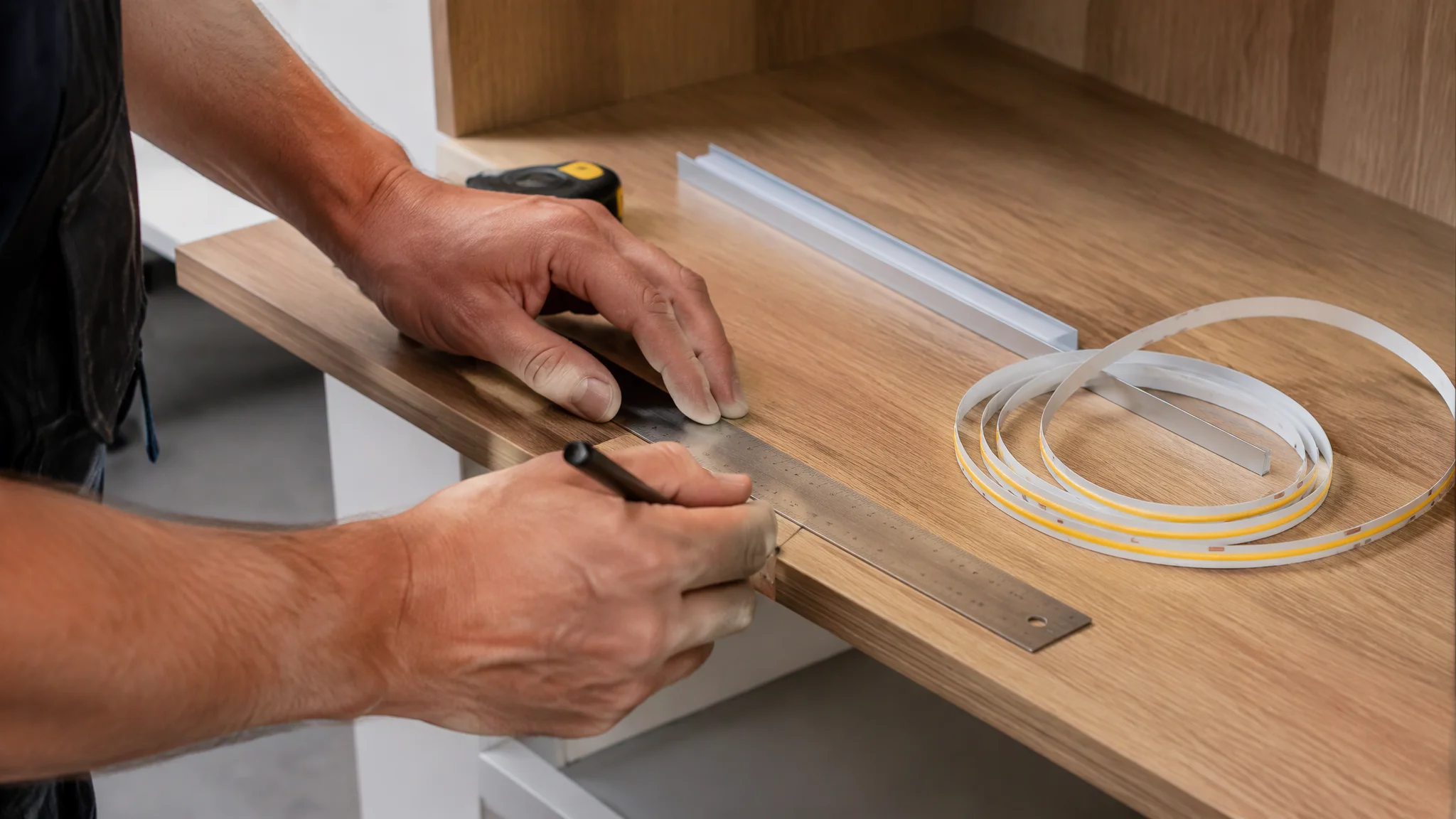 Technician measuring a cabinet shelf before cutting a COB LED strip