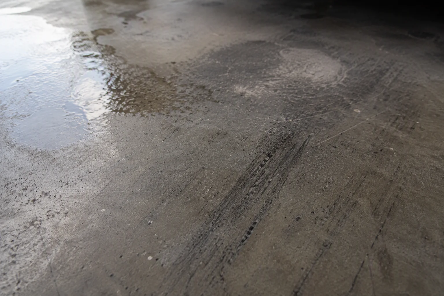 Tyre marks and surface scuffs on an unsealed polished concrete garage floor