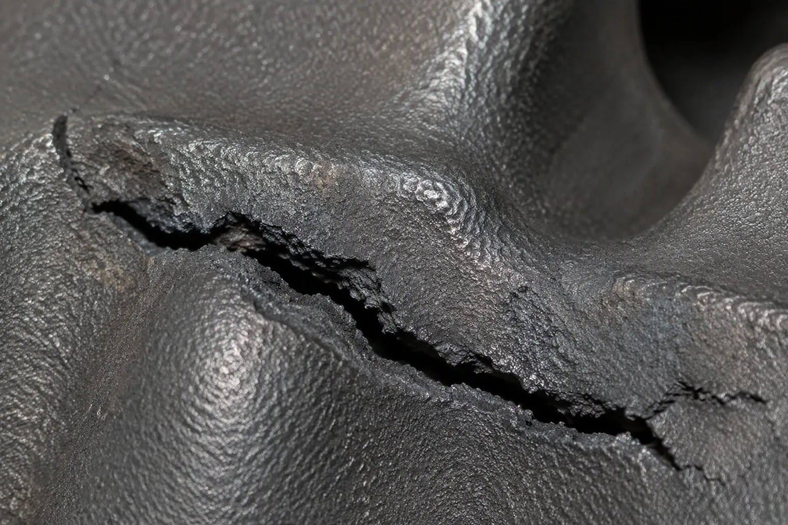 Close-up of a hot tear crack on steel casting surface — jagged, oxidized edges