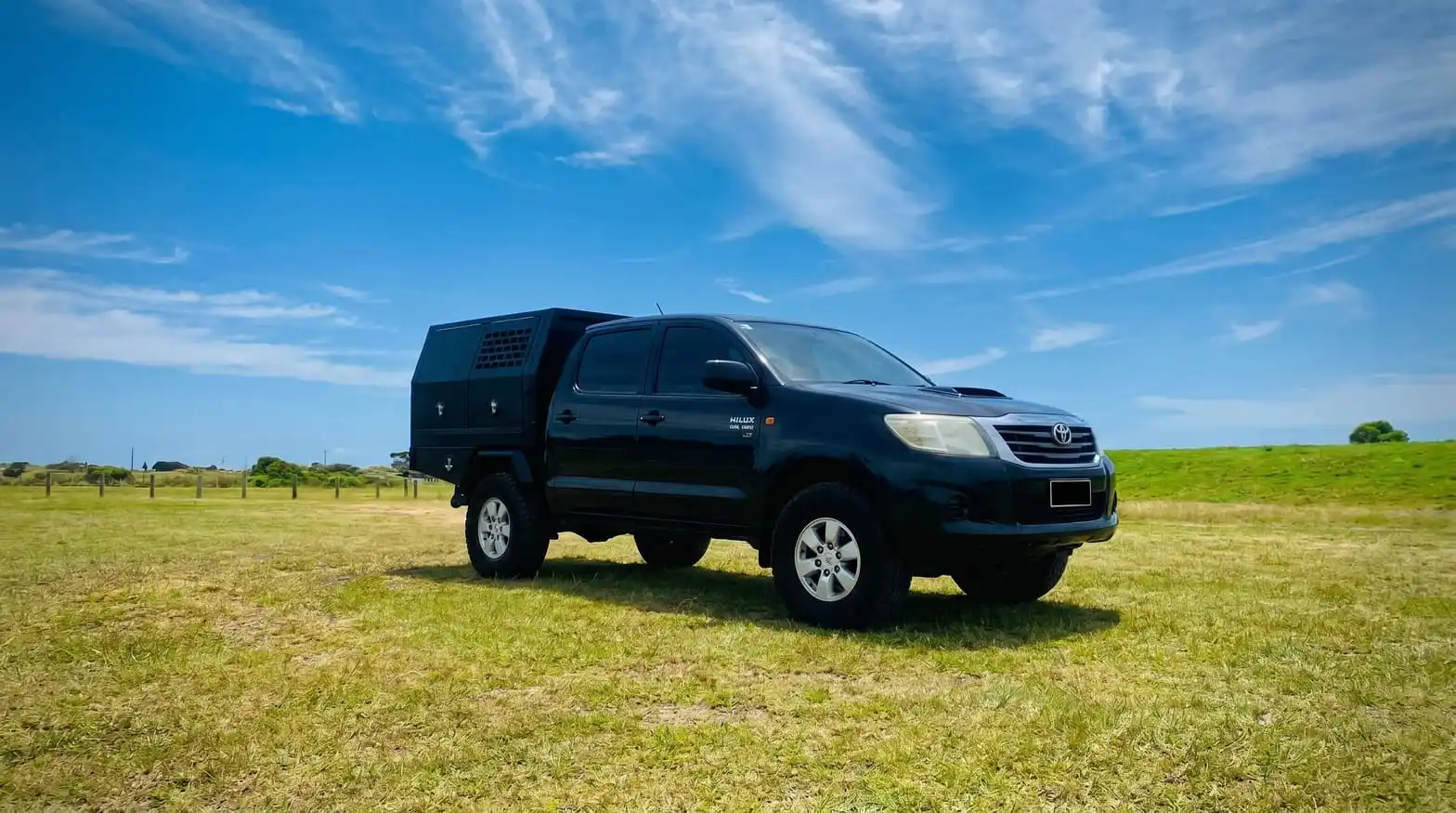 Toyota Hilux fitted with TangHan Metal aluminum ute dog box canopy parked on a green Australian paddock under blue sky