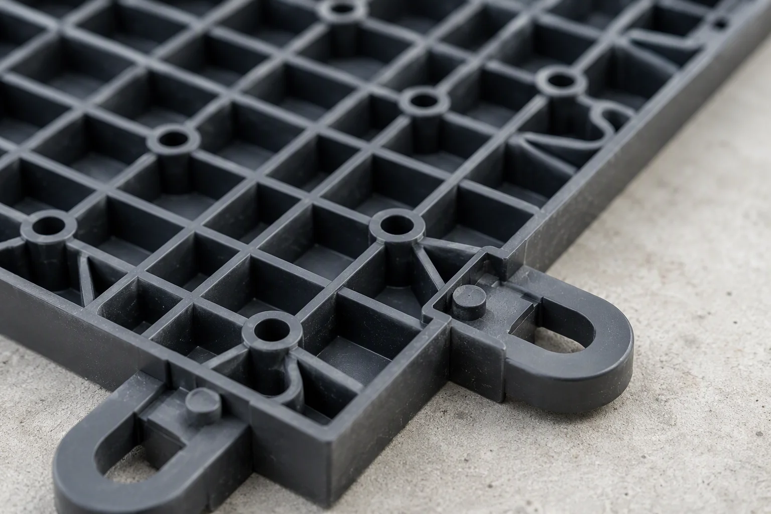 Underside of a garage floor tile showing moulded connectors and reinforcing ribs