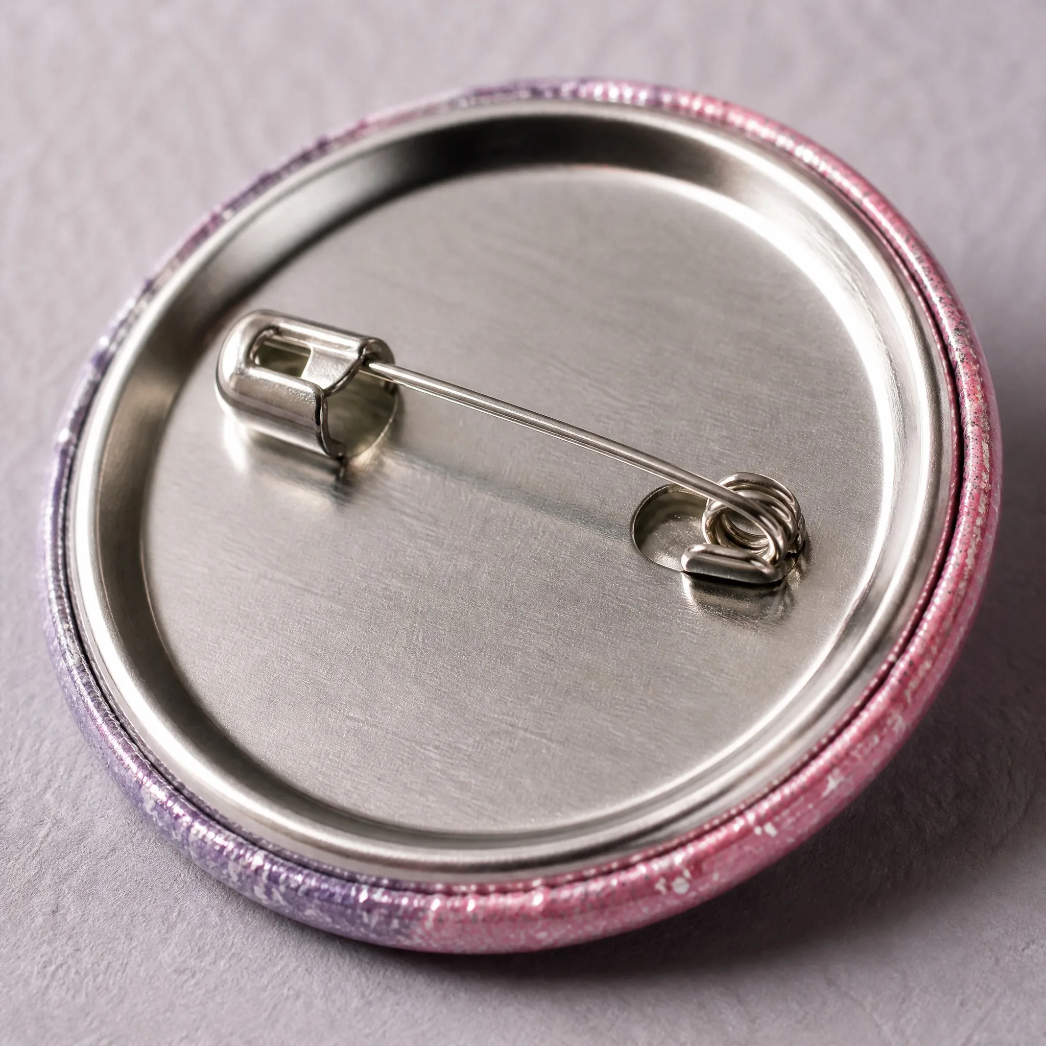 Glitter surface and safety pin back detail of button badge
