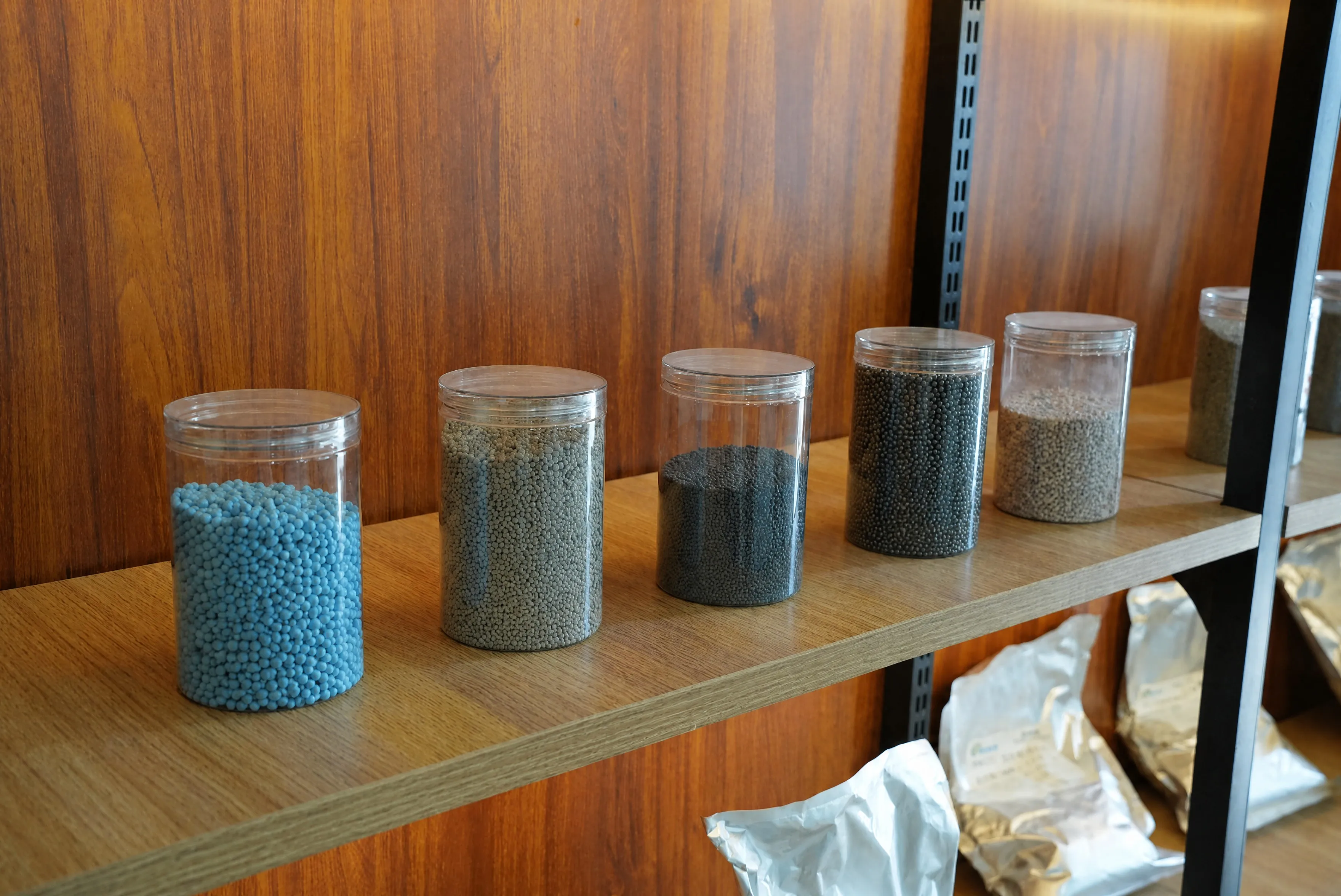 Odor control additive granules for cat litter - activated carbon, mineral granules and polymer beads in sample jars