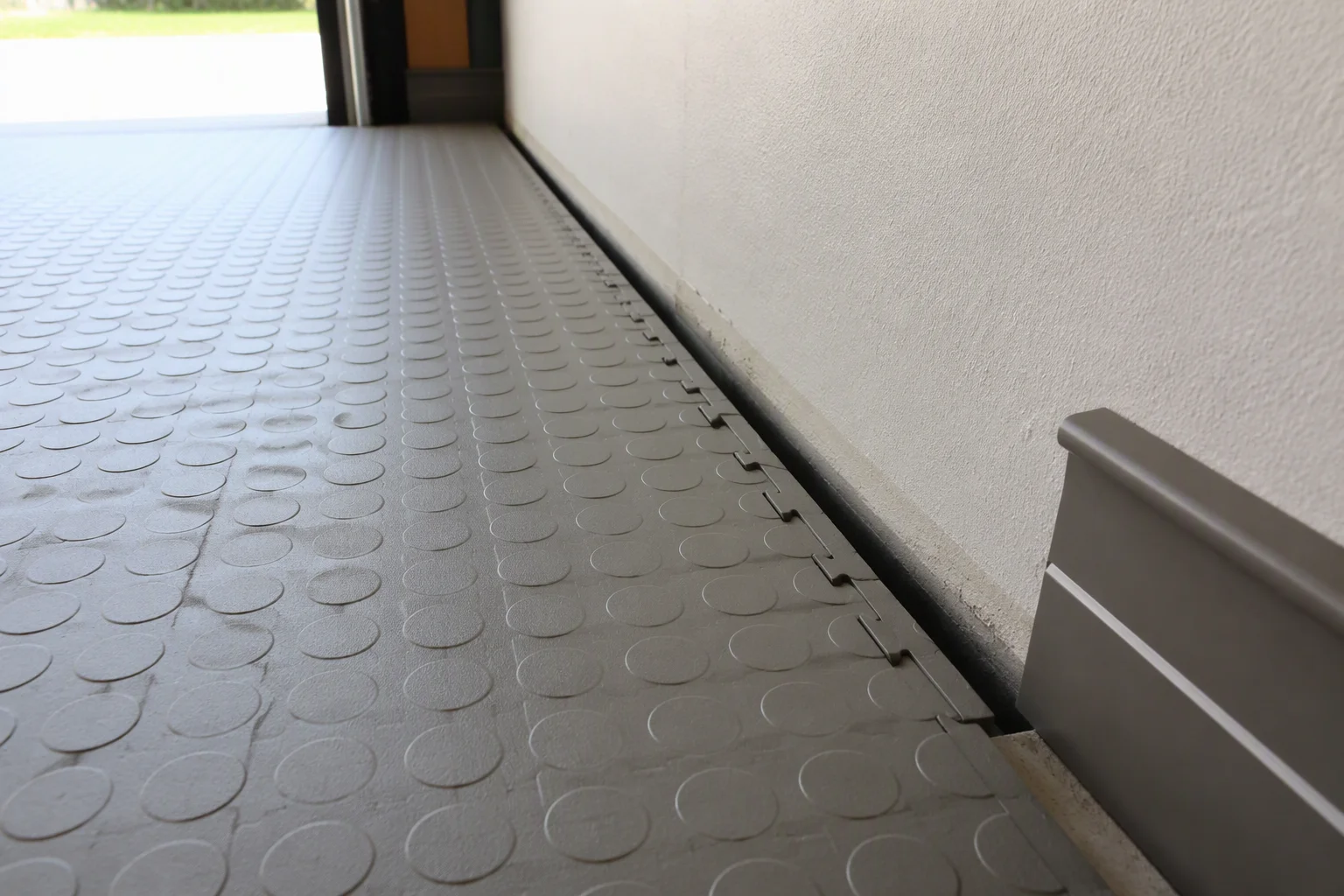 Expansion gap between garage floor tiles and the garage wall