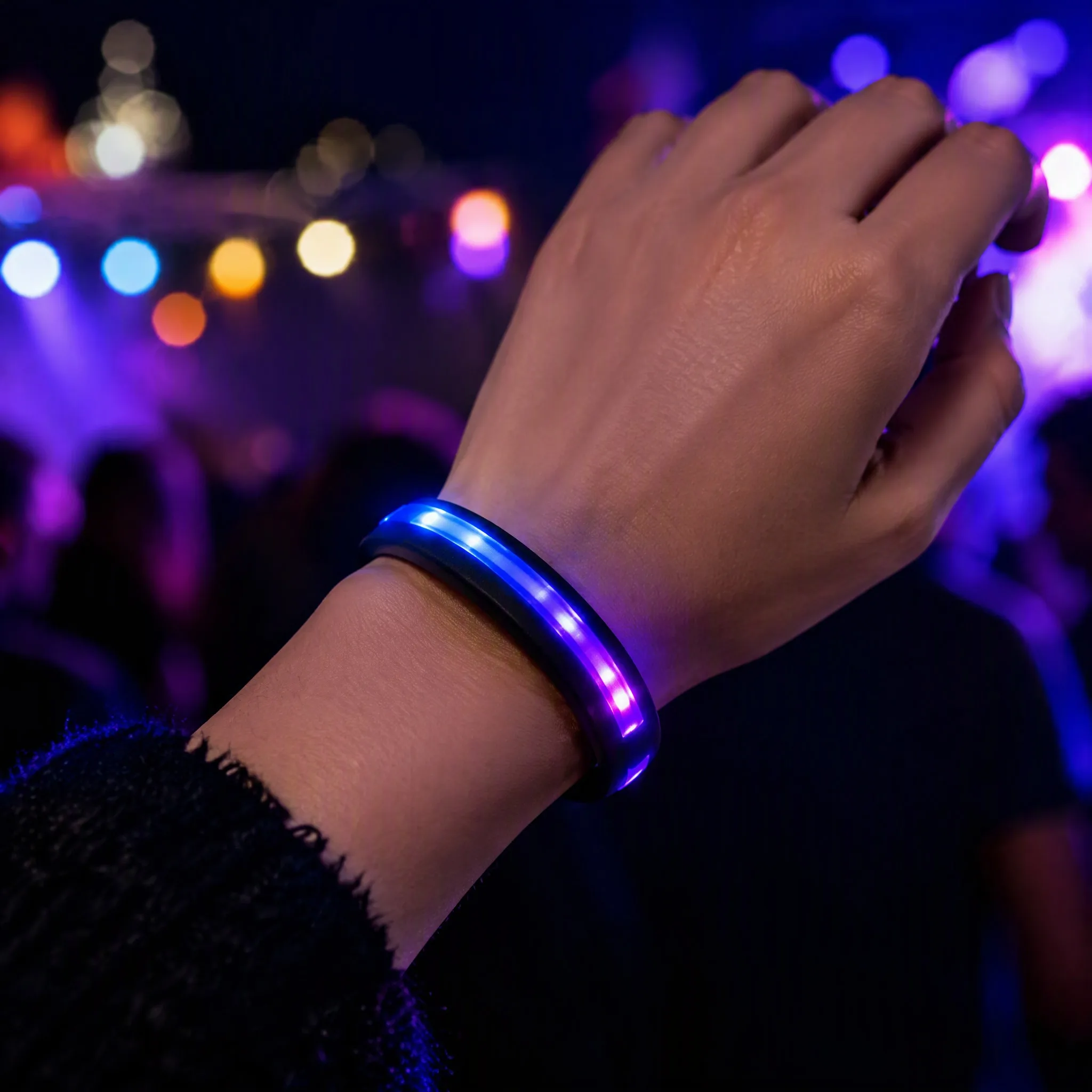 LED silicone bracelet worn on wrist glowing at a night concert