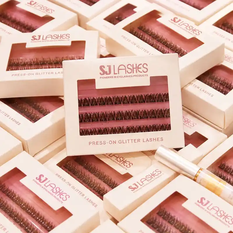 Many white press-on glitter lash window boxes fanned along with a 5ml adhesive tube - coordinated lash series packaging with one visual language