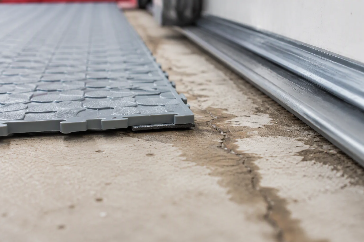 Garage floor tile edge following the slope of a concrete slab toward the garage door