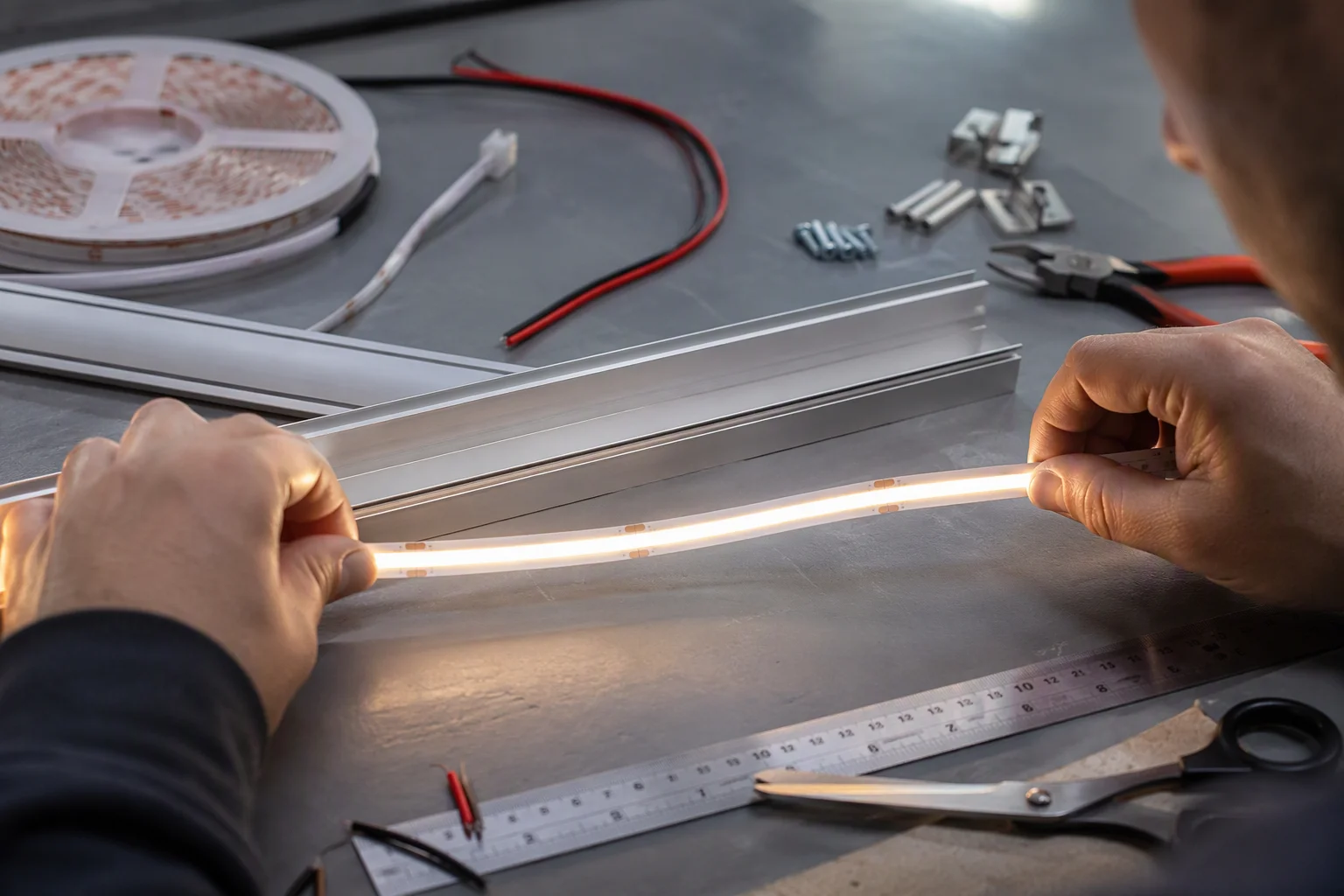 Technician preparing a cut-anywhere COB LED strip in an aluminium profile