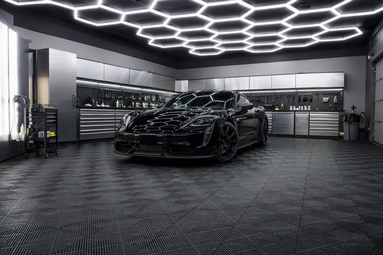 Professional car detailing workshop with interlocking garage floor tiles and hexagonal LED work lights