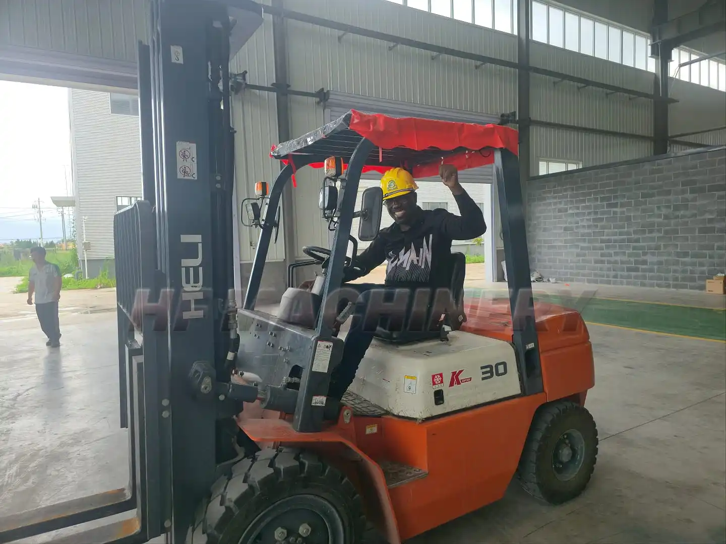 Ghanaian client smiling behind the wheel of a HELI K30 Forklift