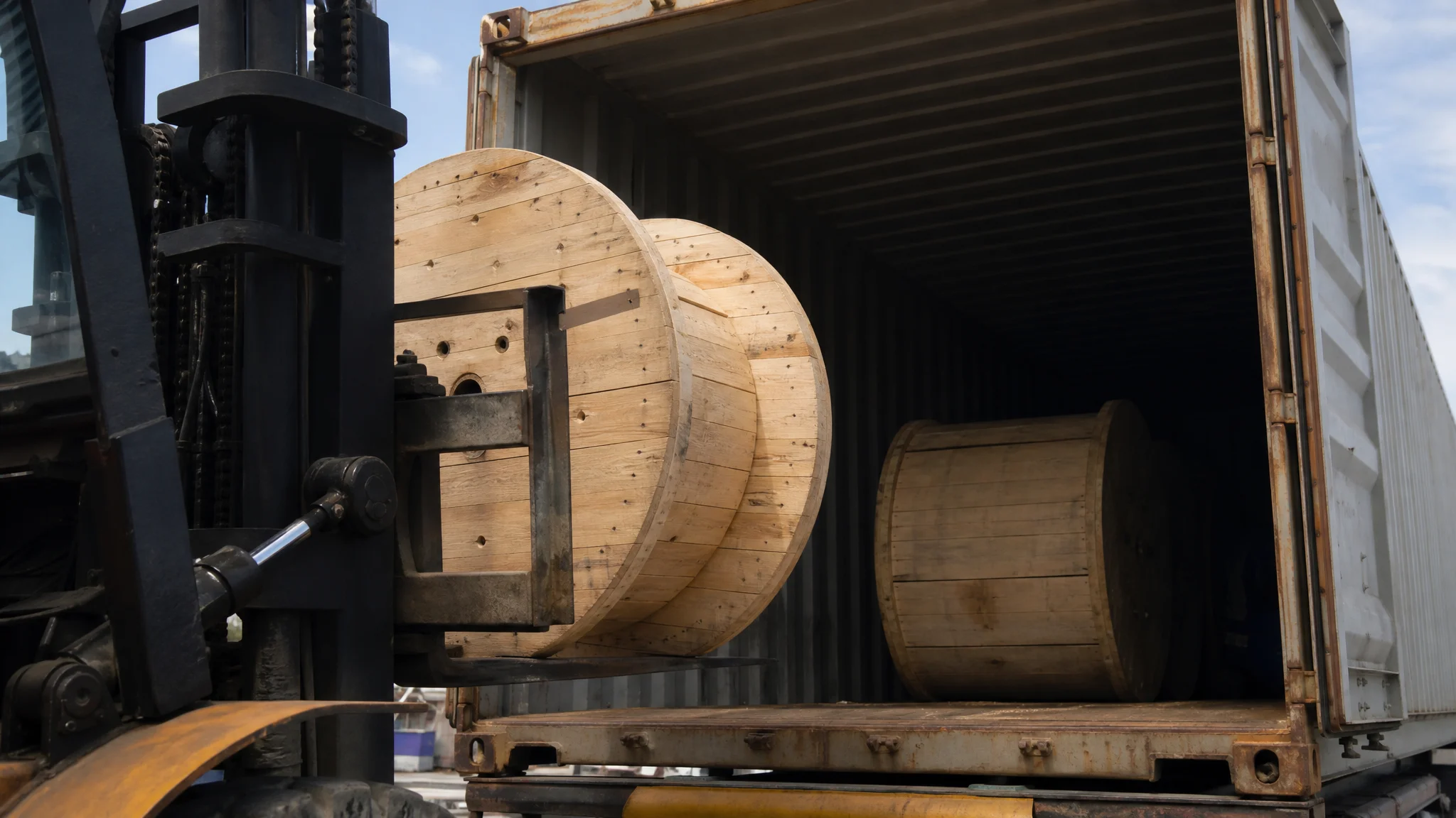 Forklift loading cable reels into a shipping container at a warehouse dock