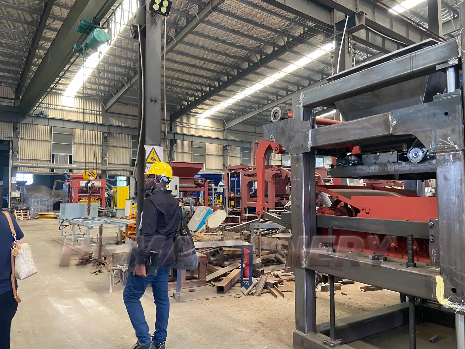 Ghanaian client inspecting large-scale machinery components in the workshop