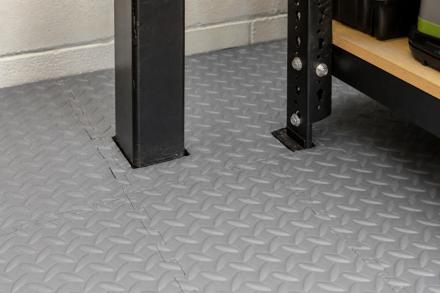 Interlocking garage floor tiles fitted neatly around a support post and workbench leg