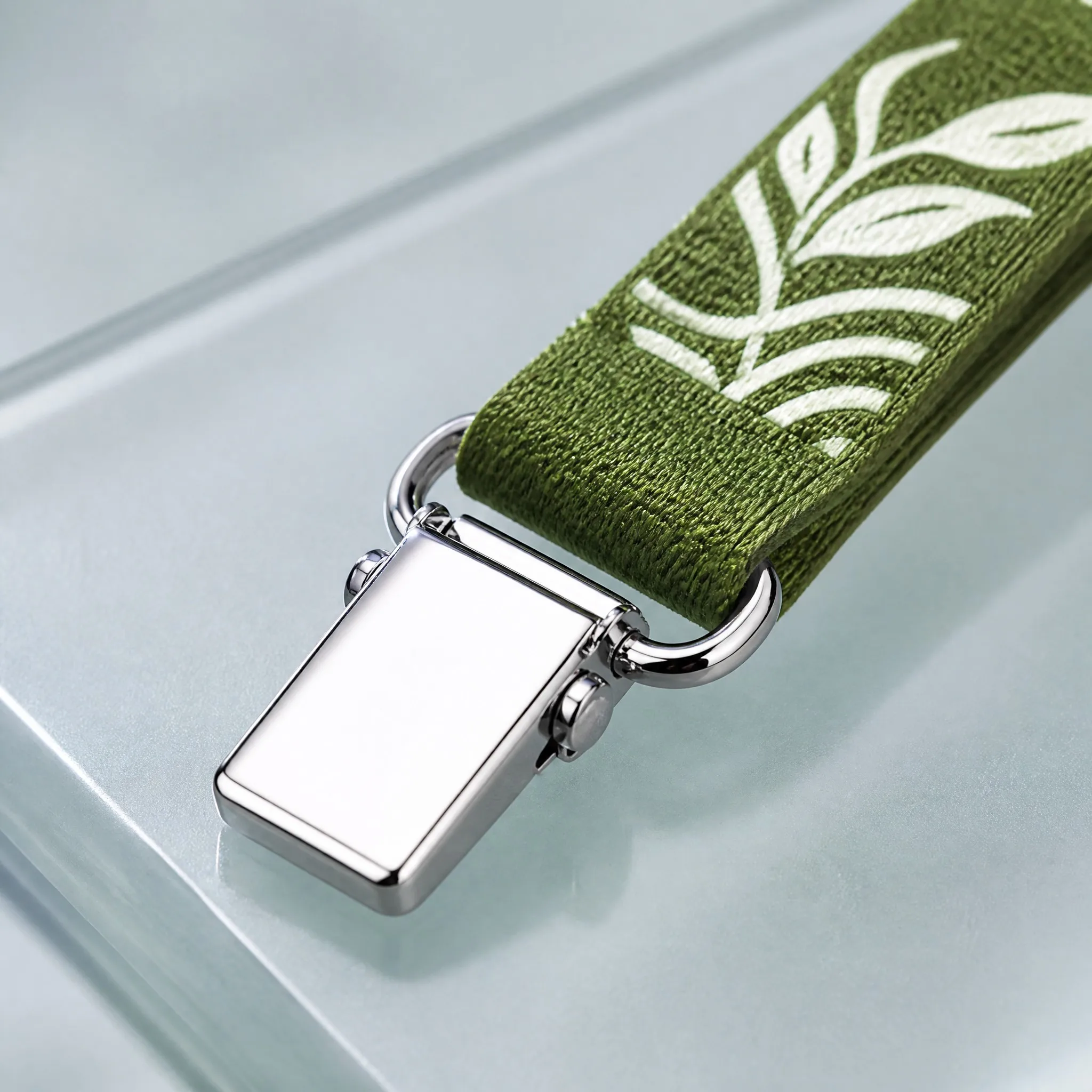 Close-up of moss green recycled PET webbing and polished silver magnetic badge clip
