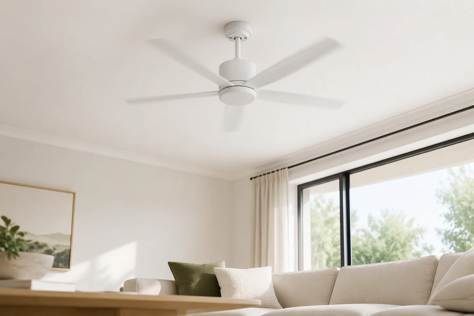 White DC ceiling fan rotating on the ceiling of a bright living room