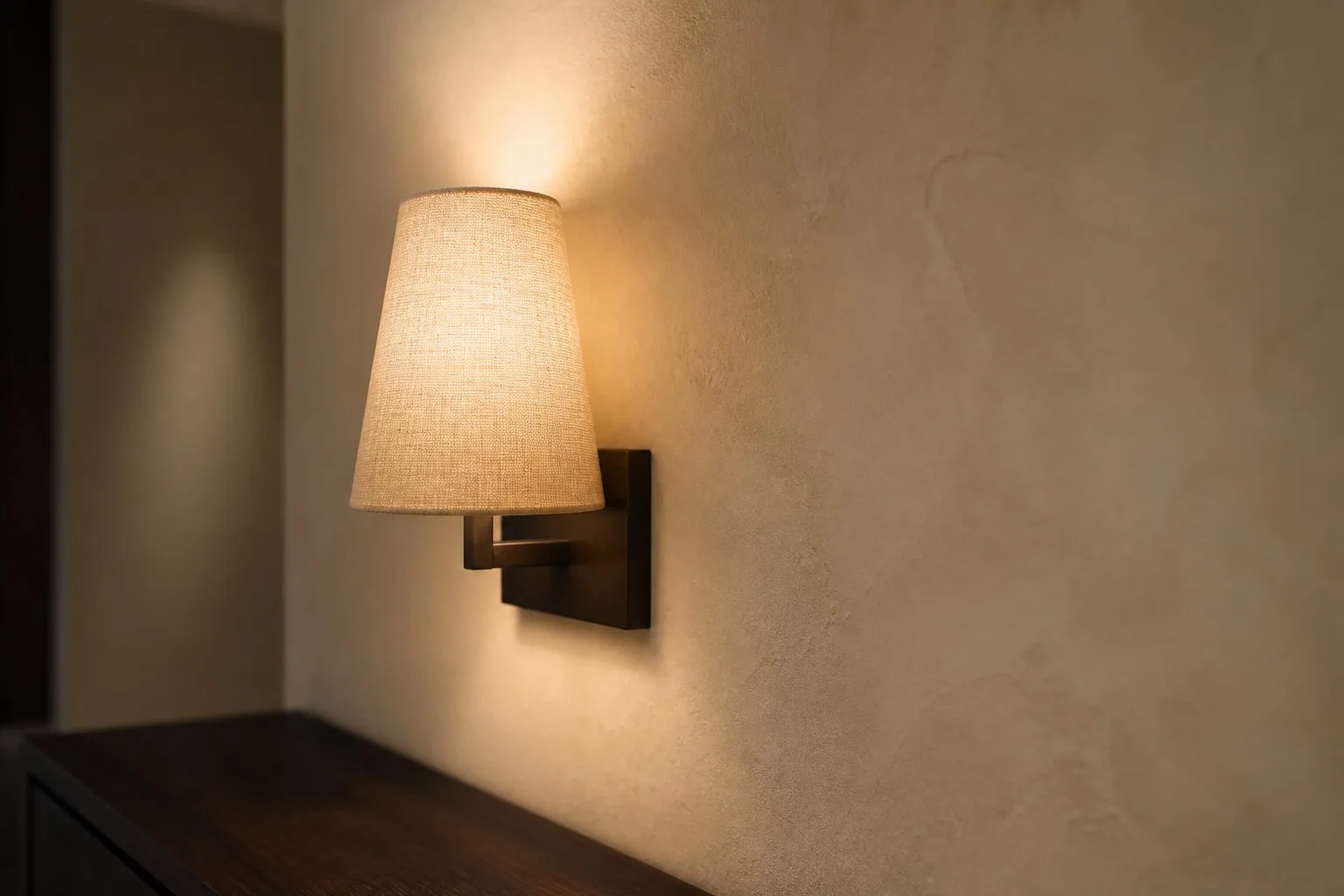 Wall sconce with a woven linen shade showing the weave and the soft edge of diffused light