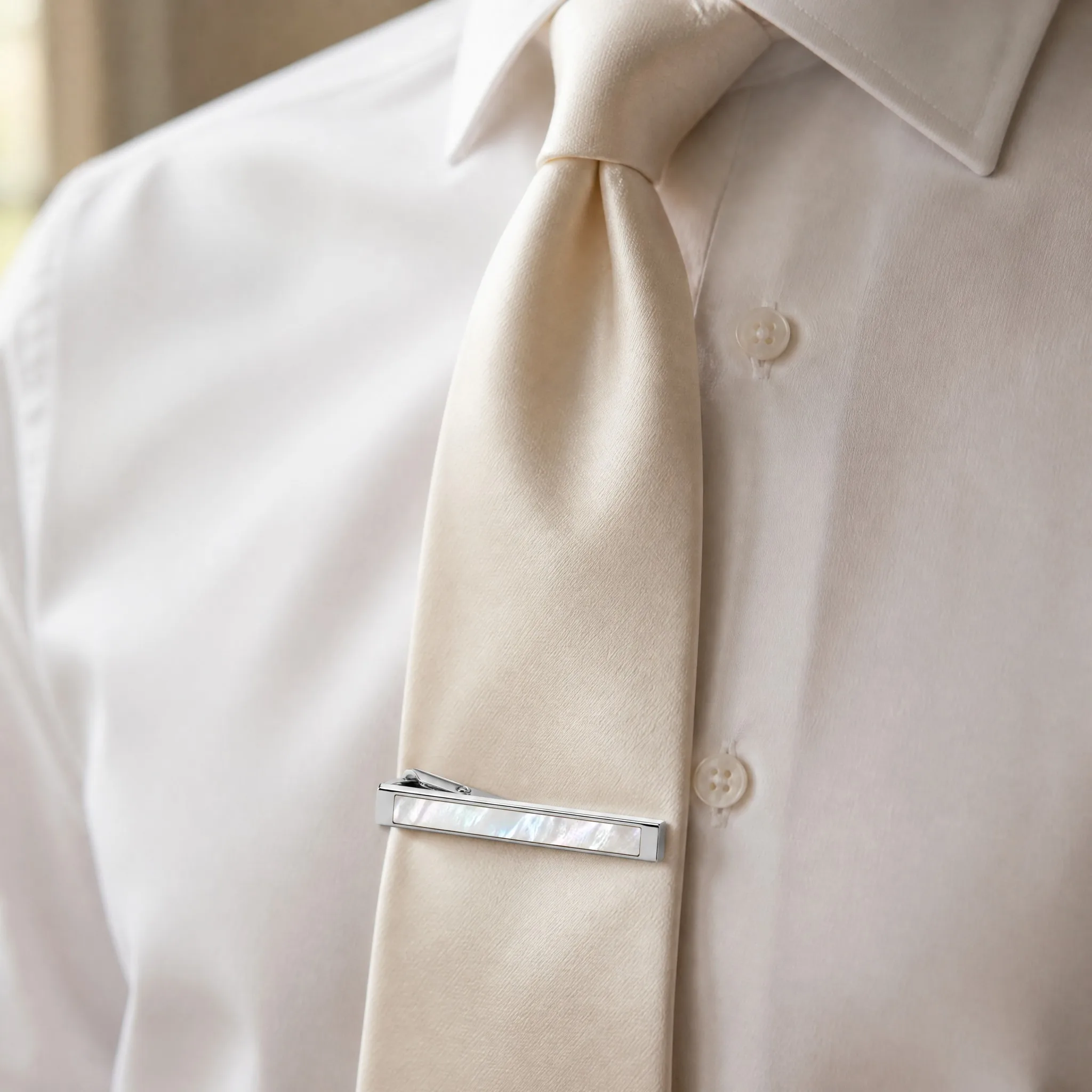 Mother of pearl tie clip worn on ivory silk tie