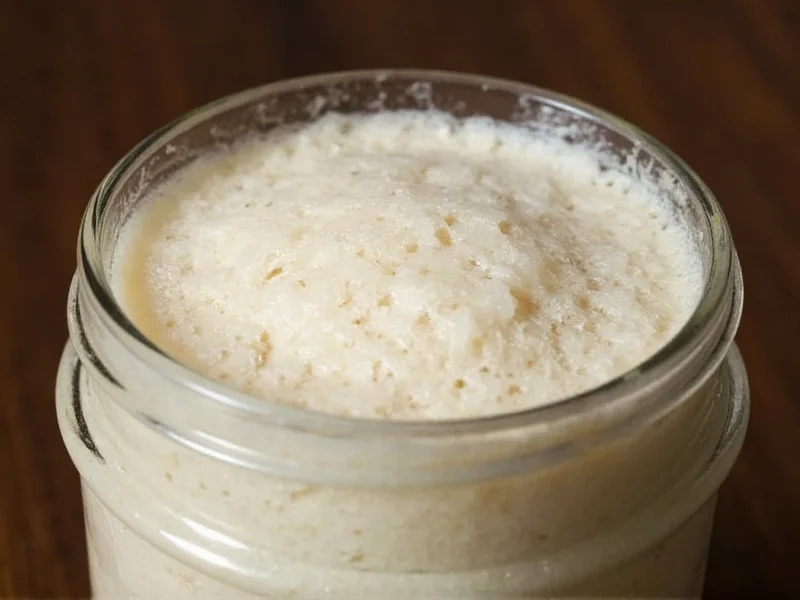 Sourdough starter bubbling vigorously in glass jar