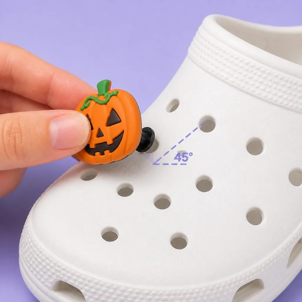 Hand inserting a jack-o-lantern charm into a clog ventilation hole at a 45 degree angle