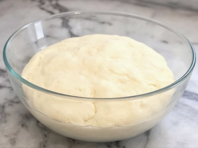 Pizza dough rising in glass bowl