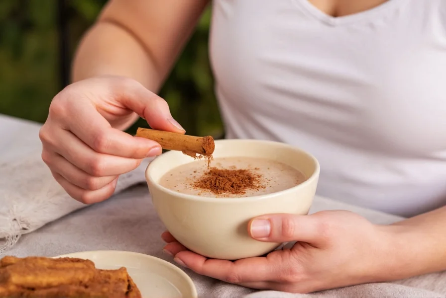 Person measuring cinnamon into a morning smoothie bowl, demonstrating practical daily use of Ceylon cinnamon for health benefits
