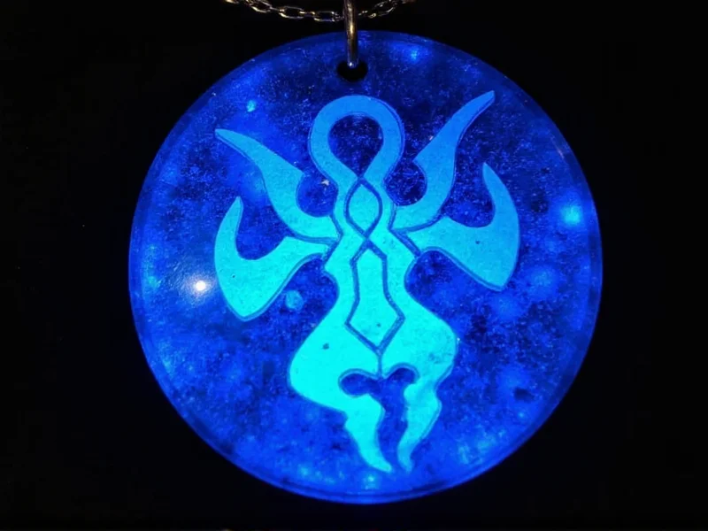 Blue resin pendant with Draenei symbols glowing under light