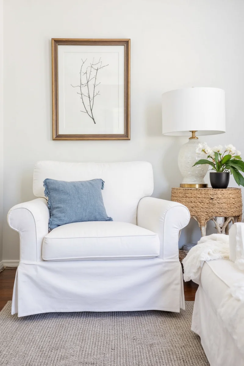 White slipcovered chair next to a colorful throw blanket and toy basket