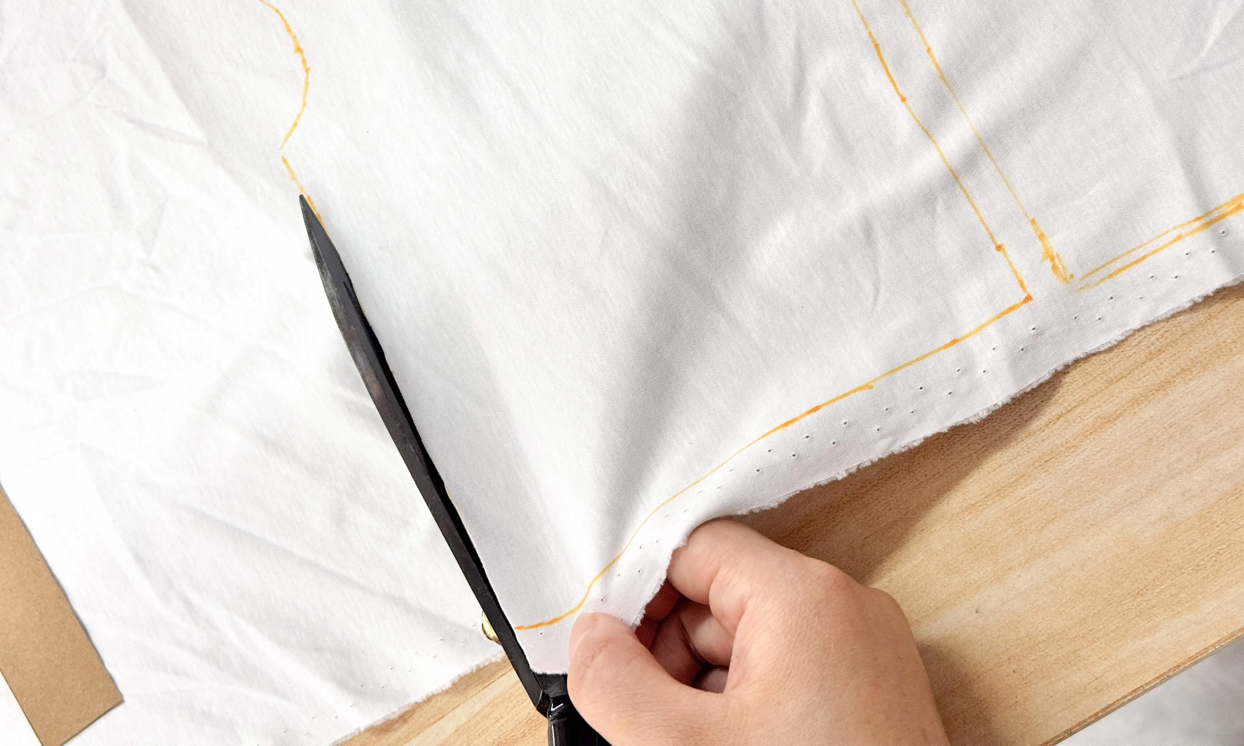 Cutting fabric along orange guide lines with dressmaking shears