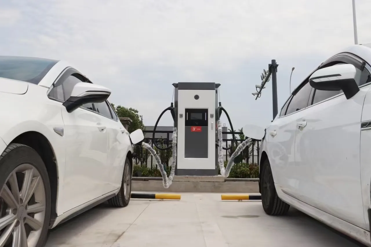 Two electric vehicles charging at the same time from one dual-gun 240 kW charging cabinet with overhead cable support arms