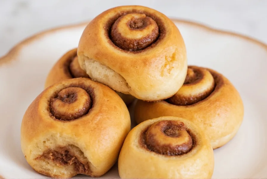 Freshly baked homemade cinnamon rolls with cream cheese icing on white ceramic plate