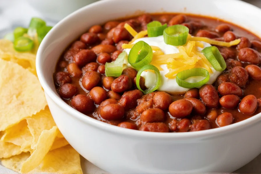 Homemade chili with beans served in a bowl with toppings like sour cream, cheese, and green onions