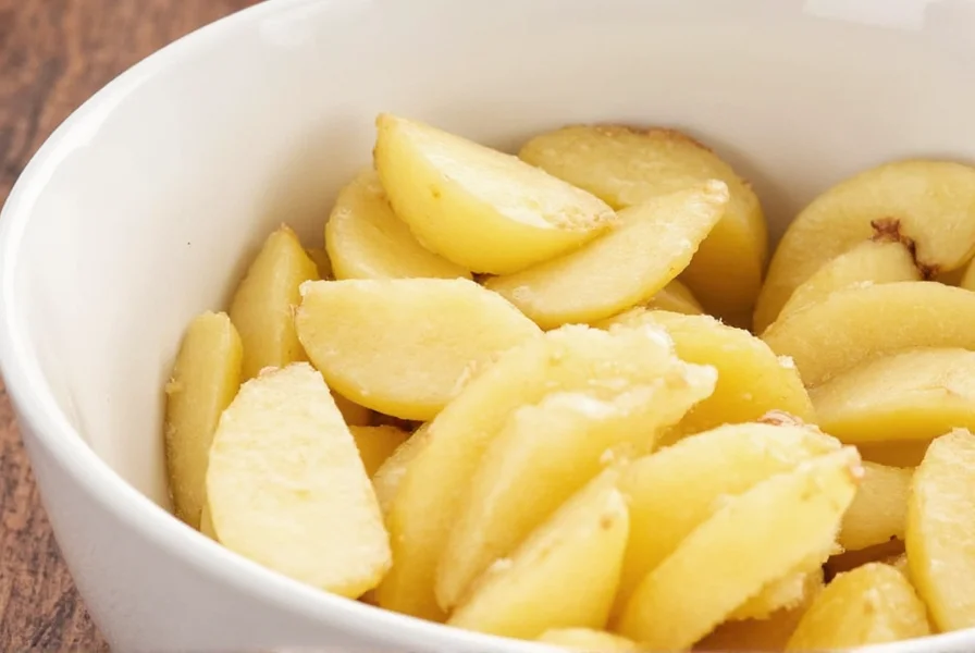 Close-up of hand using teaspoon to peel ginger root, showing thin layer of skin being removed with minimal waste