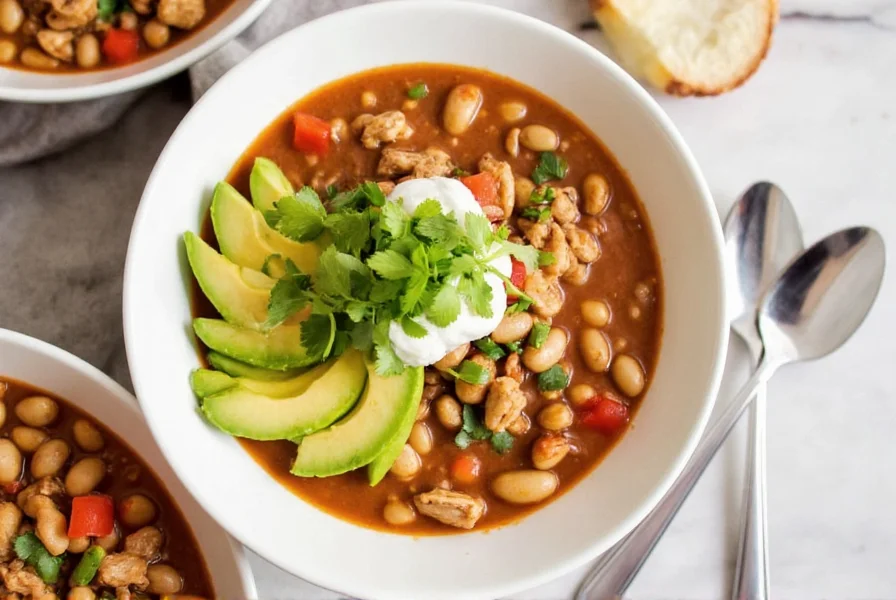 Finished bowl of instant pot white bean chicken chili with toppings like avocado and cilantro