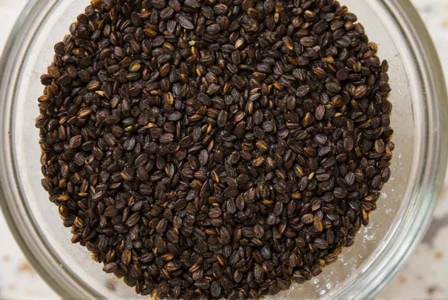 Close-up of Nigella sativa seeds in a glass bowl with oil droplets