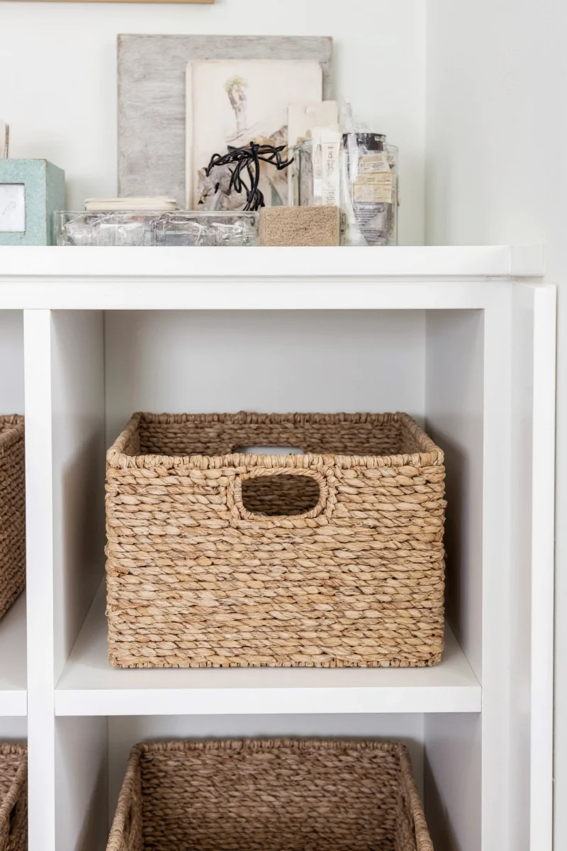 Narrow basket hidden behind a bookshelf collecting cords