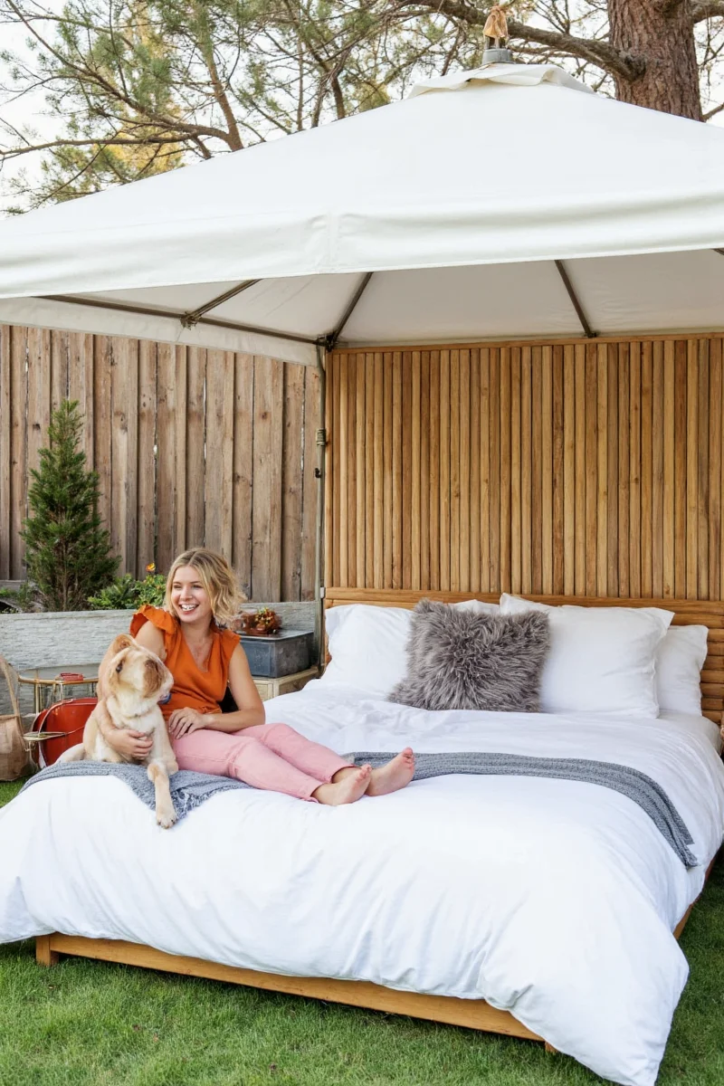 A couple lying in a canopy bed outdoors with their golden retriever snuggled between them on a custom pet bed.