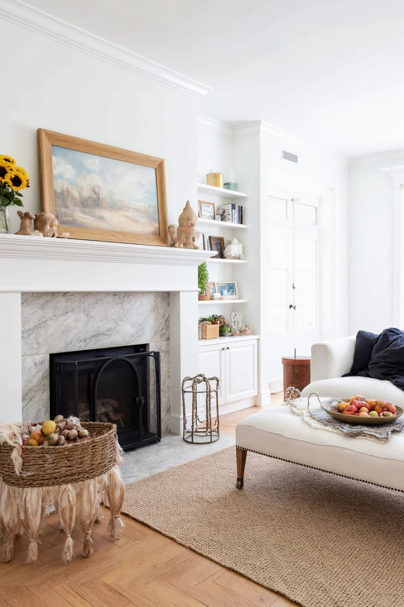 Stylishly decorated white fireplace mantle with candles, books, and photos