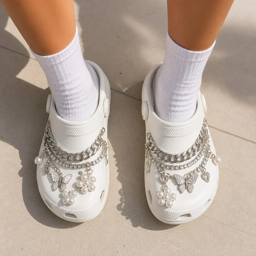 Luxury crystal and chain clog charms worn on foot with white socks on a sunlit walkway