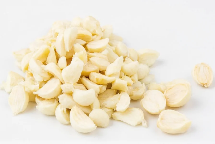 Four medium garlic cloves next to measuring spoons showing 1½ to 2 teaspoons of minced garlic