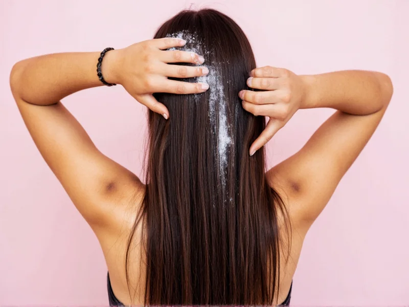 Applying homemade dry shampoo to dark hair